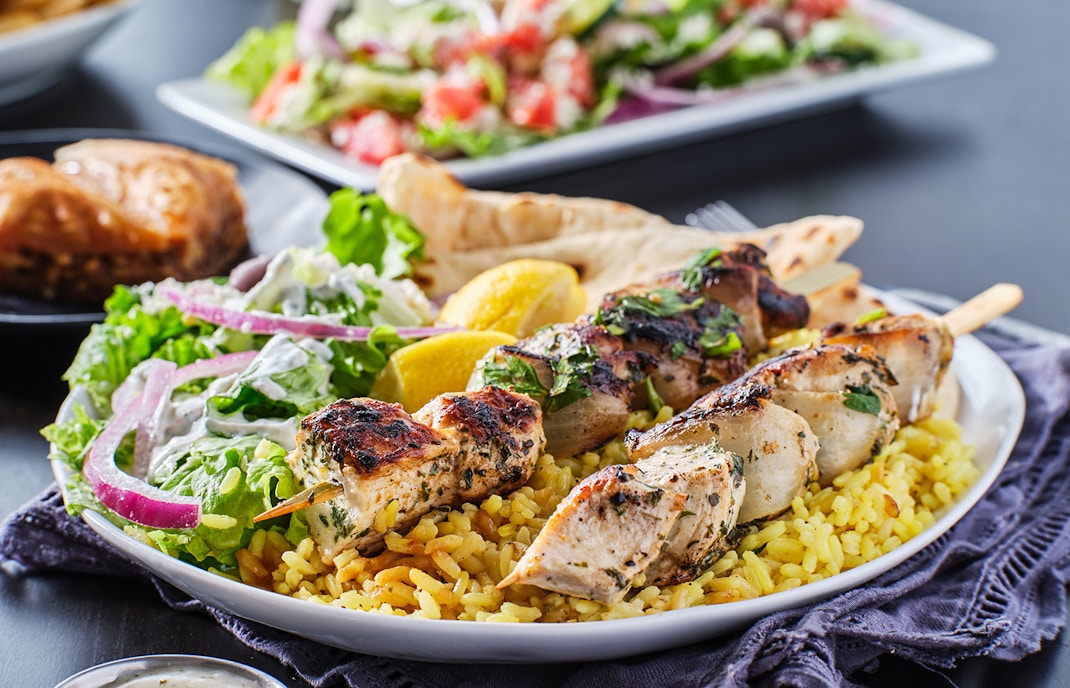 Grilled chicken skewers on rice with salad and lemon, Mediterranean BBQ.
