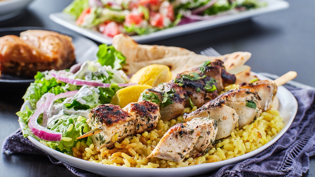 Grilled chicken skewers on rice with salad and lemon, Mediterranean BBQ.