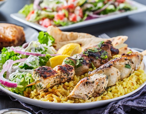 Grilled chicken skewers on rice with salad and lemon, Mediterranean BBQ.