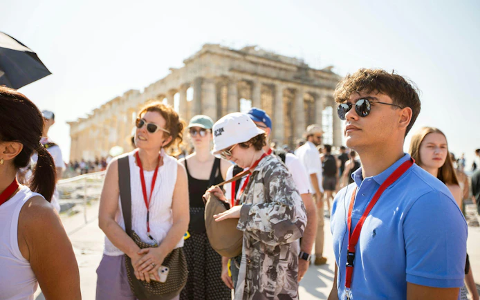 Tourists with audio guides exploring the Acropolis and Parthenon in Athens.