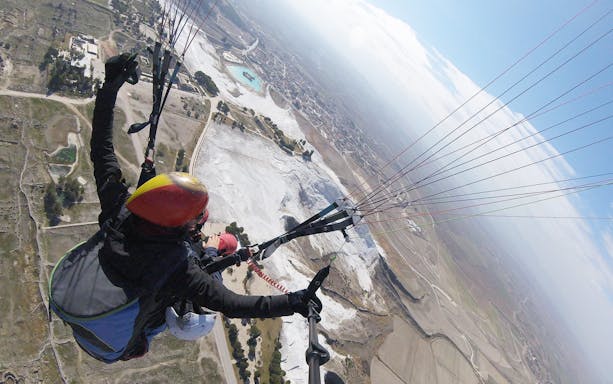 Tandem paragliding over Pamukkale's travertine terraces, Turkey.
