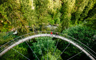 Visitors walking on the Capilano Suspension Bridge surrounded by lush forest in Vancouver, Canada.