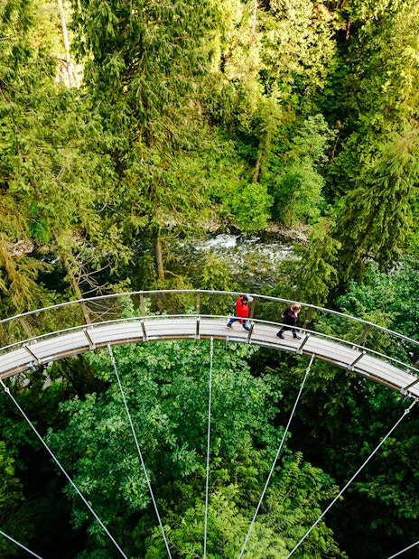 Visitors walking on the Capilano Suspension Bridge surrounded by lush forest in Vancouver, Canada.