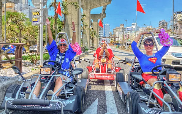 Participants in costumes enjoying a go-karting experience on a street in Okinawa.