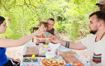 Family enjoying seafood lunch on Funzi Island excursion, surrounded by lush greenery.
