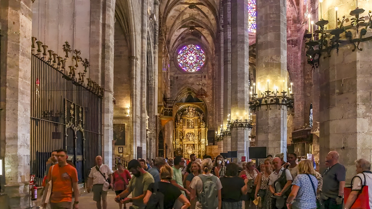 Visitors inside Palma Cathedral admiring Gothic architecture and stained glass windows, Palma, Spain.