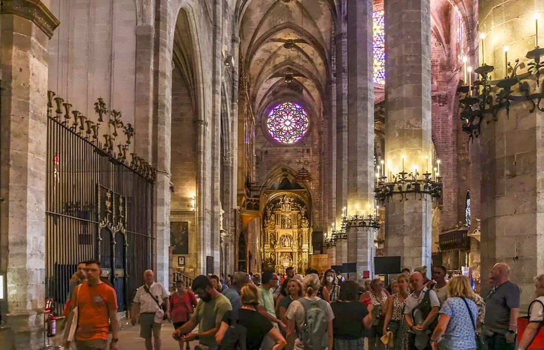 Visitors inside Palma Cathedral exploring its Gothic architecture and stained glass windows in Palma, Spain