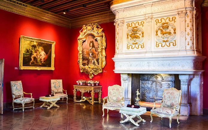 Chenonceau Castle interior with ornate fireplace and classic paintings.