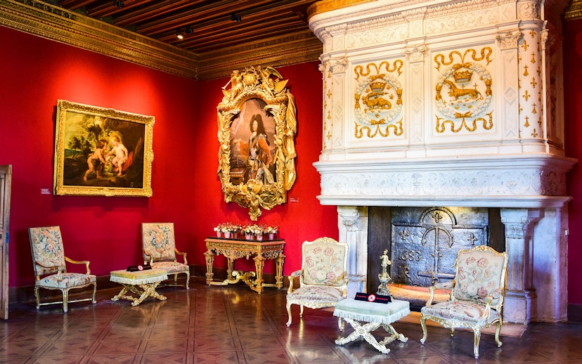 Chenonceau Castle interior with ornate fireplace and classic paintings.