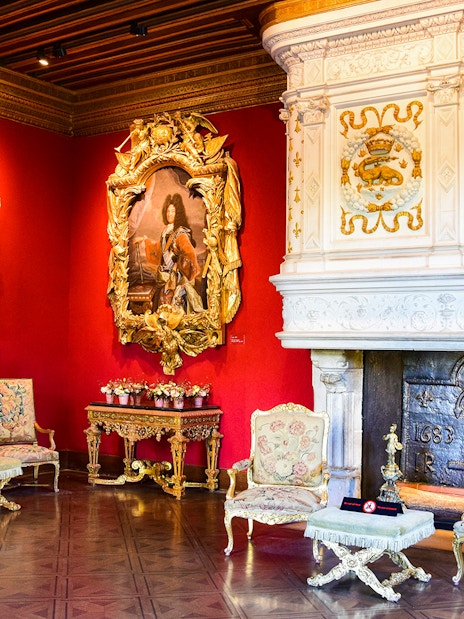 Chenonceau Castle interior with ornate fireplace and classic paintings.
