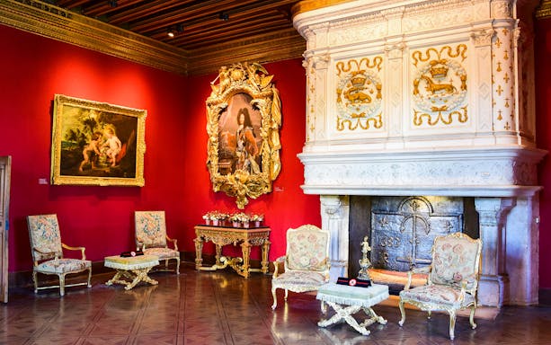 Chenonceau Castle interior with ornate fireplace and classic paintings.