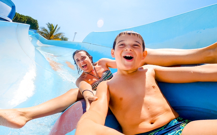 Mother and son enjoying a water slide at a water park.