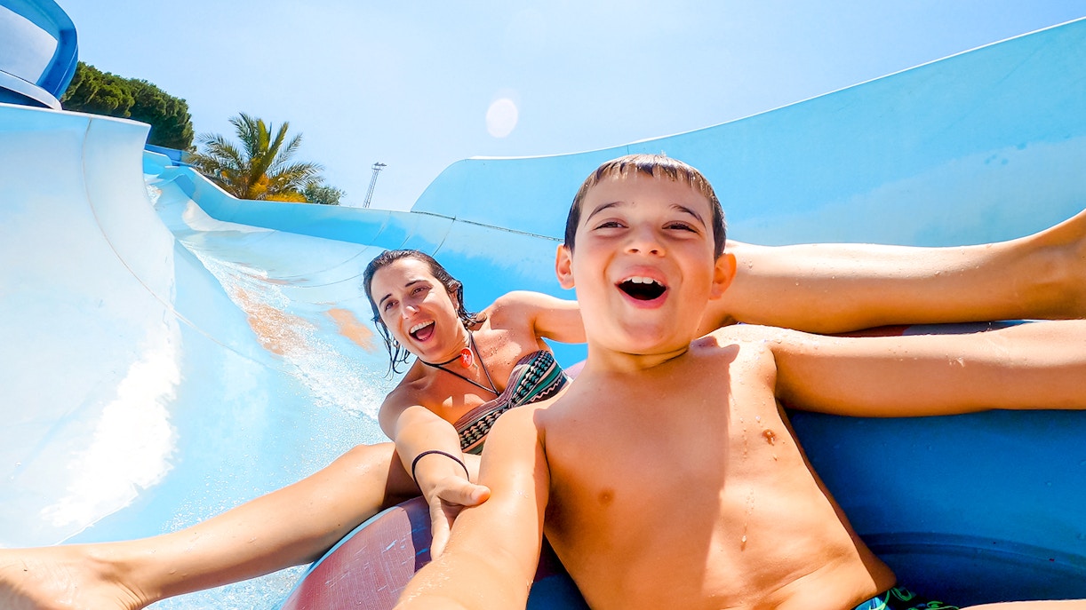 Mother and son enjoying a water slide at a water park.