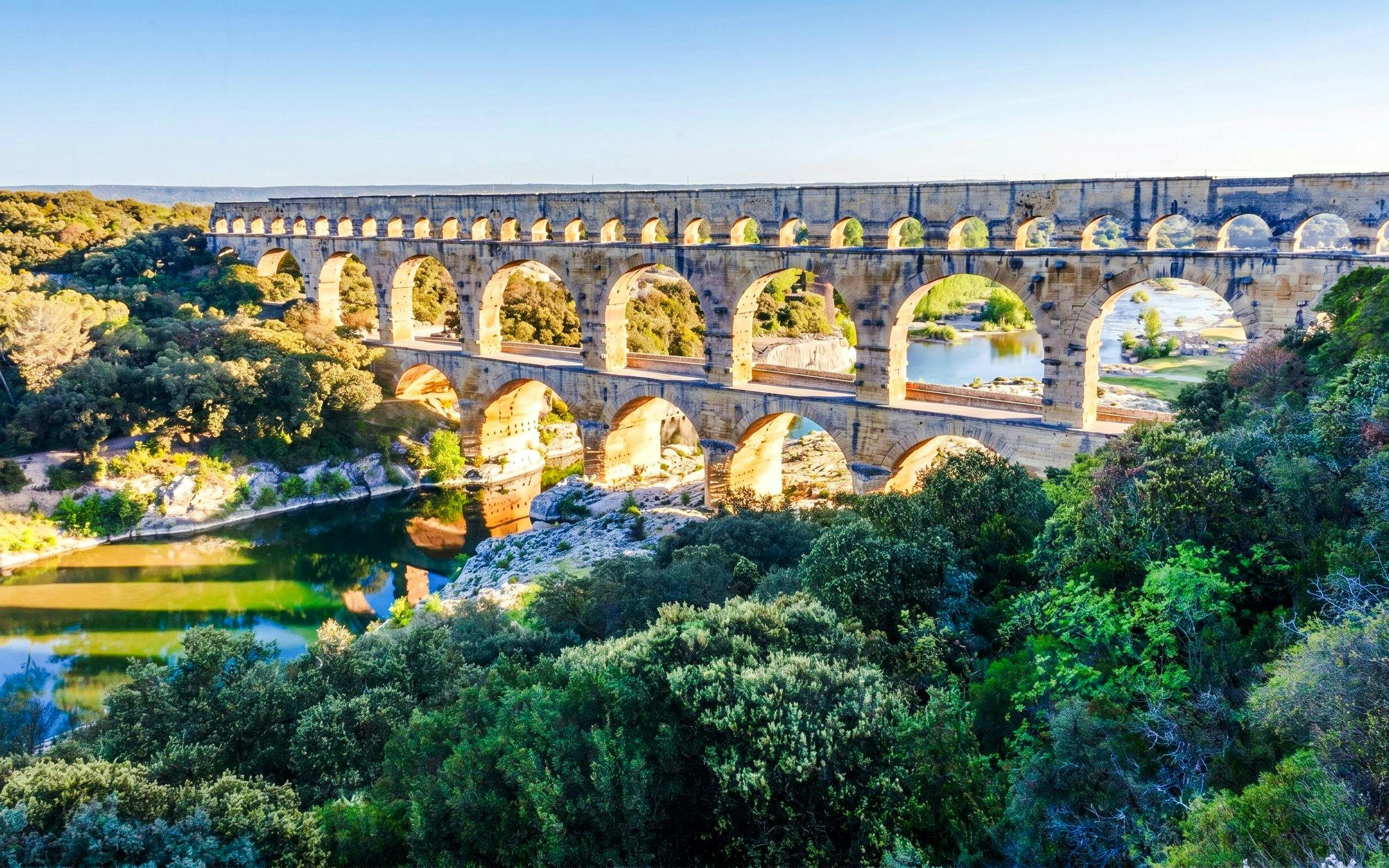 Pont du Gard aqueduct spanning a river in a lush landscape, France.