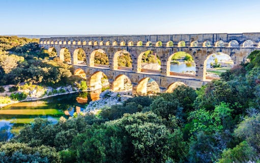 Pont du Gard aqueduct spanning a river in a lush landscape, France.