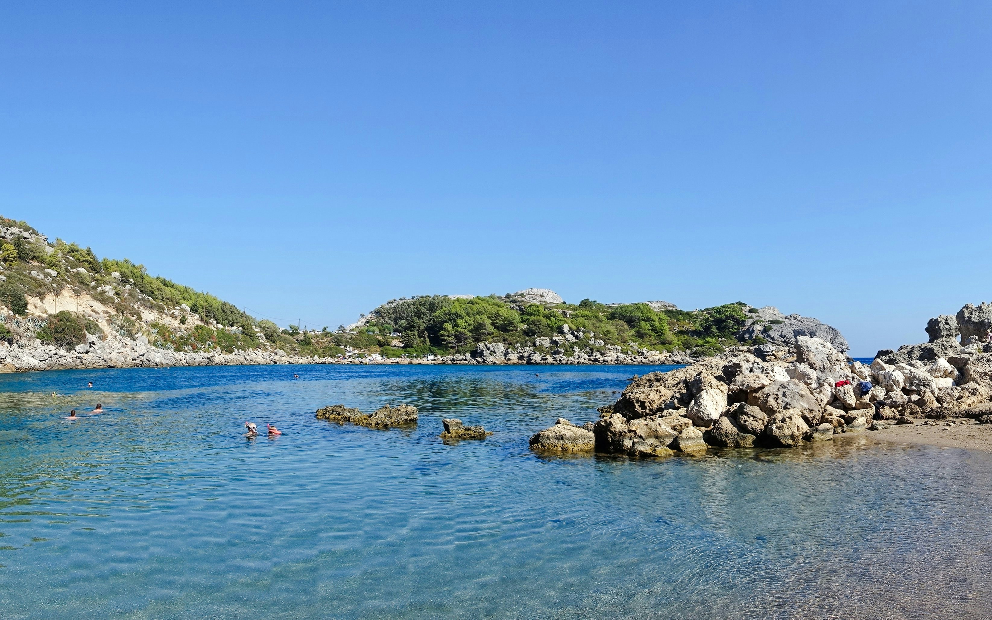 Ladiko Bay Beach with swimmers and rocky shoreline during a Rhodes cruise, Greece.