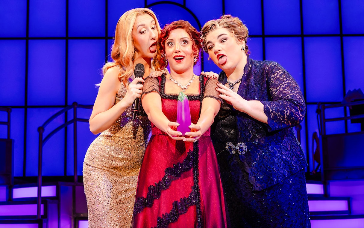 Three performers on stage during Titanique West End show, holding a prop and singing.