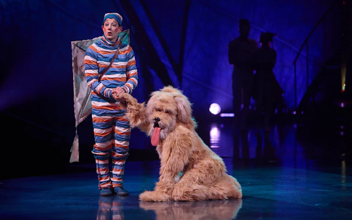 Performer in colorful costume with large dog on stage during Kooza Brisbane show.