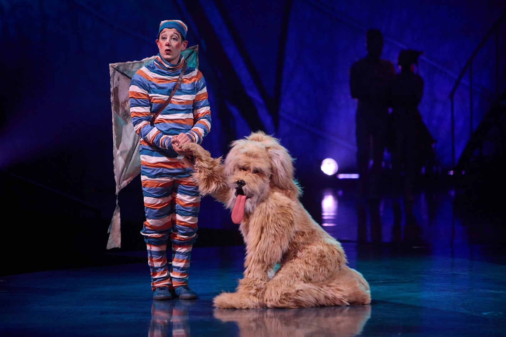 Performer in colorful costume with large dog on stage during Kooza Brisbane show.