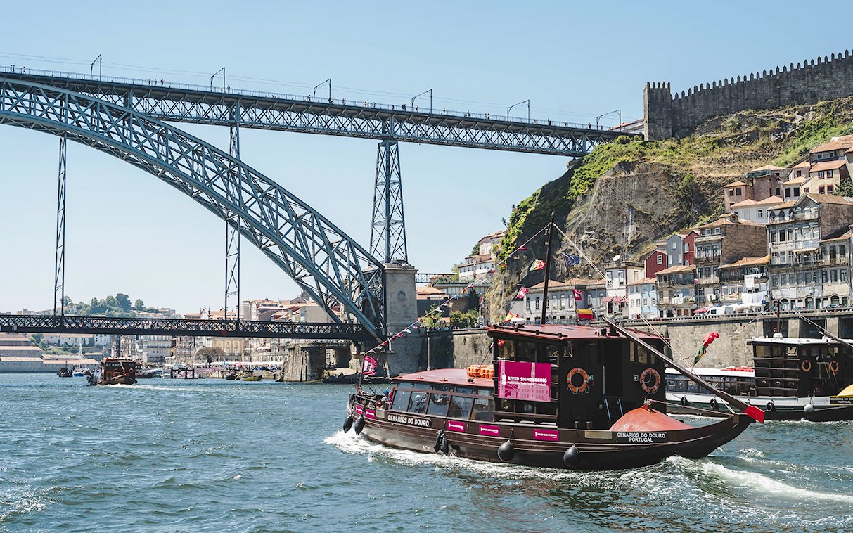 Tourist boat on Douro River near Dom Luís I Bridge, Porto, Portugal.