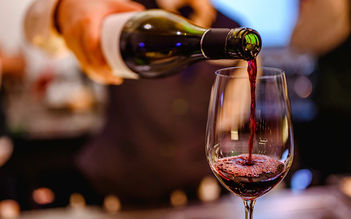 Pouring red wine into a glass at a wine tasting event.