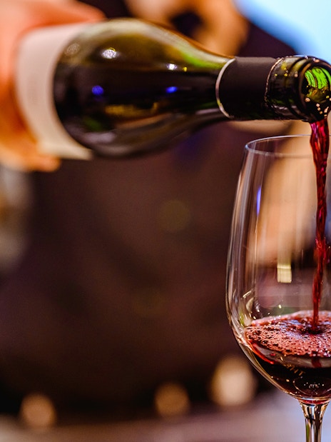 Pouring red wine into a glass at a wine tasting event.