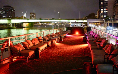 Seine River dinner cruise deck with seating, Paris city lights in background.