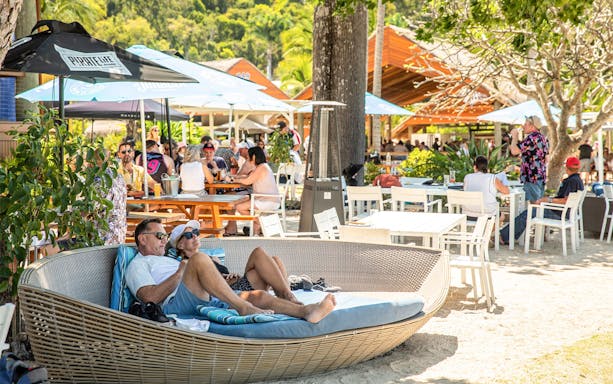 Outdoor lounge area with people relaxing and dining, Falls to Paradise Guided Day Tour.