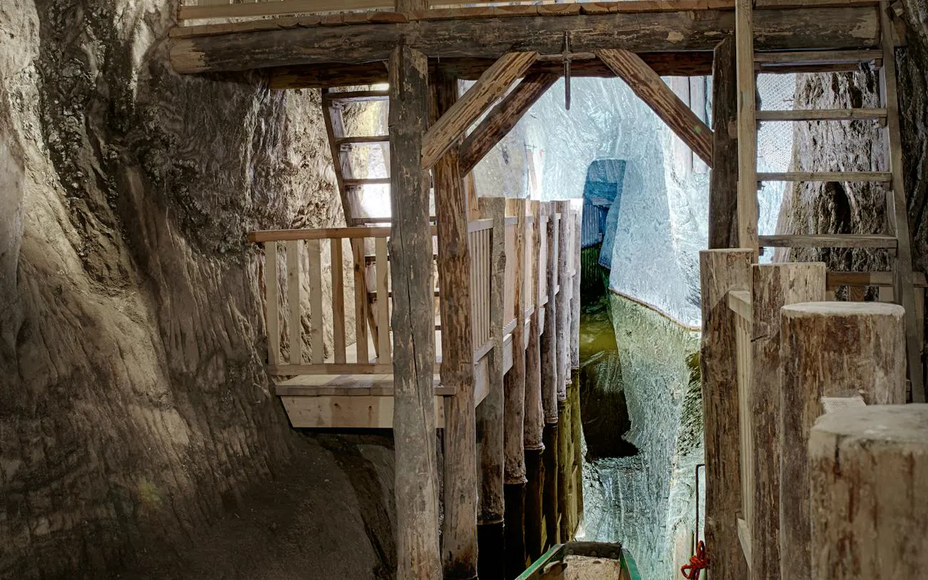 Underground wooden walkway in Bochnia Salt Mine, Krakow, with visible salt walls and water channel.