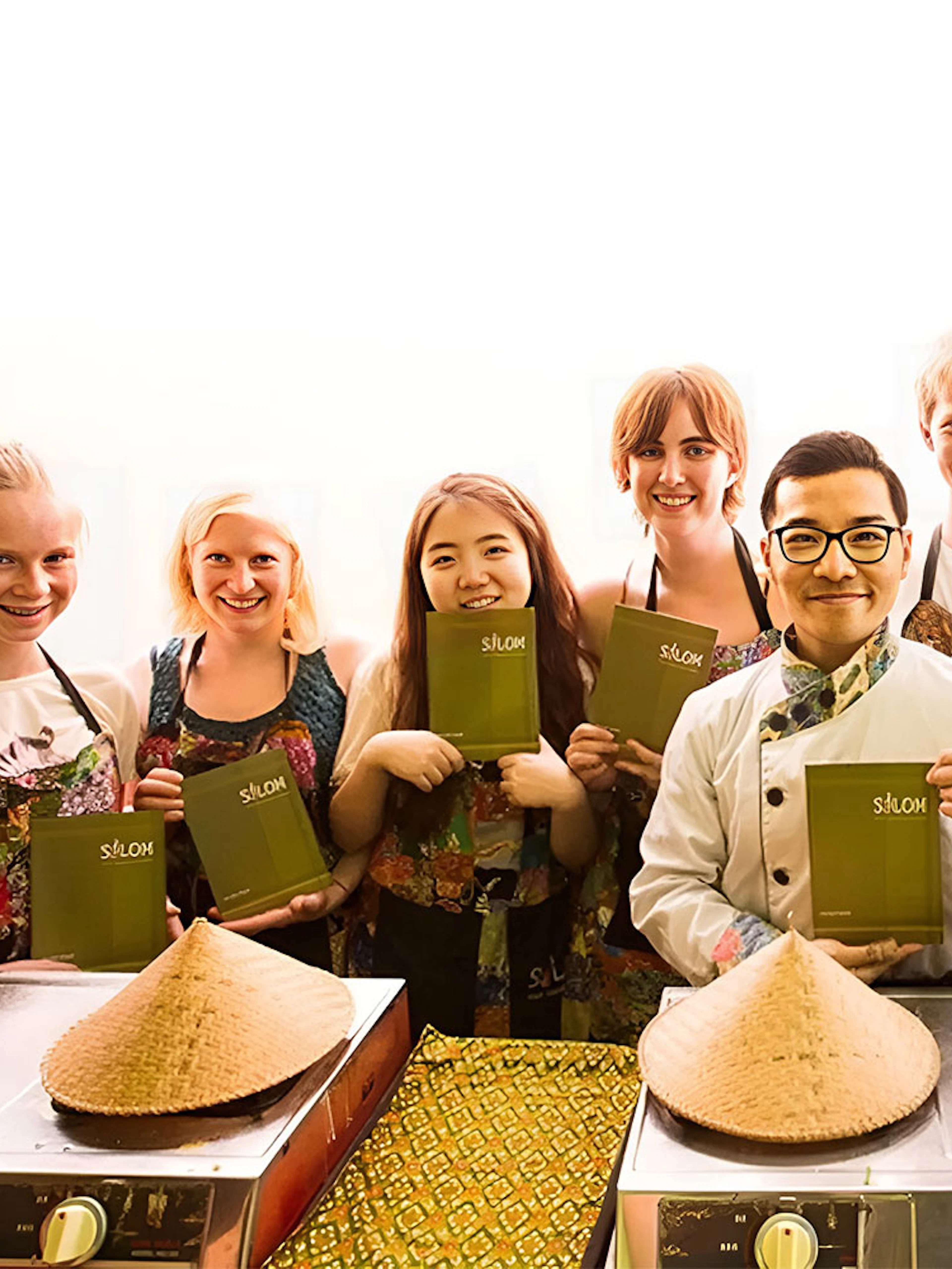 Participants holding recipe books at Silom Thai Cooking School in Bangkok.