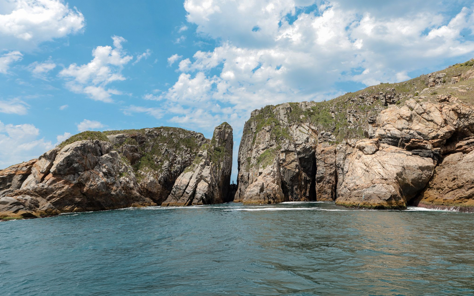 Boat tour approaching Fenda de Nossa Senhora in Arraial do Cabo, Brazil.