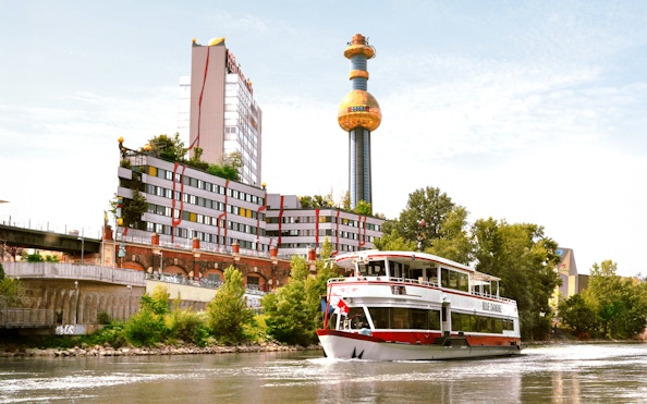 MS Blue Danube cruise on Danube Canal, Vienna, with Spittelau incineration plant in background.