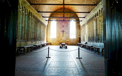 Mont-Saint-Michel Abbey interior with stone columns and wooden benches.