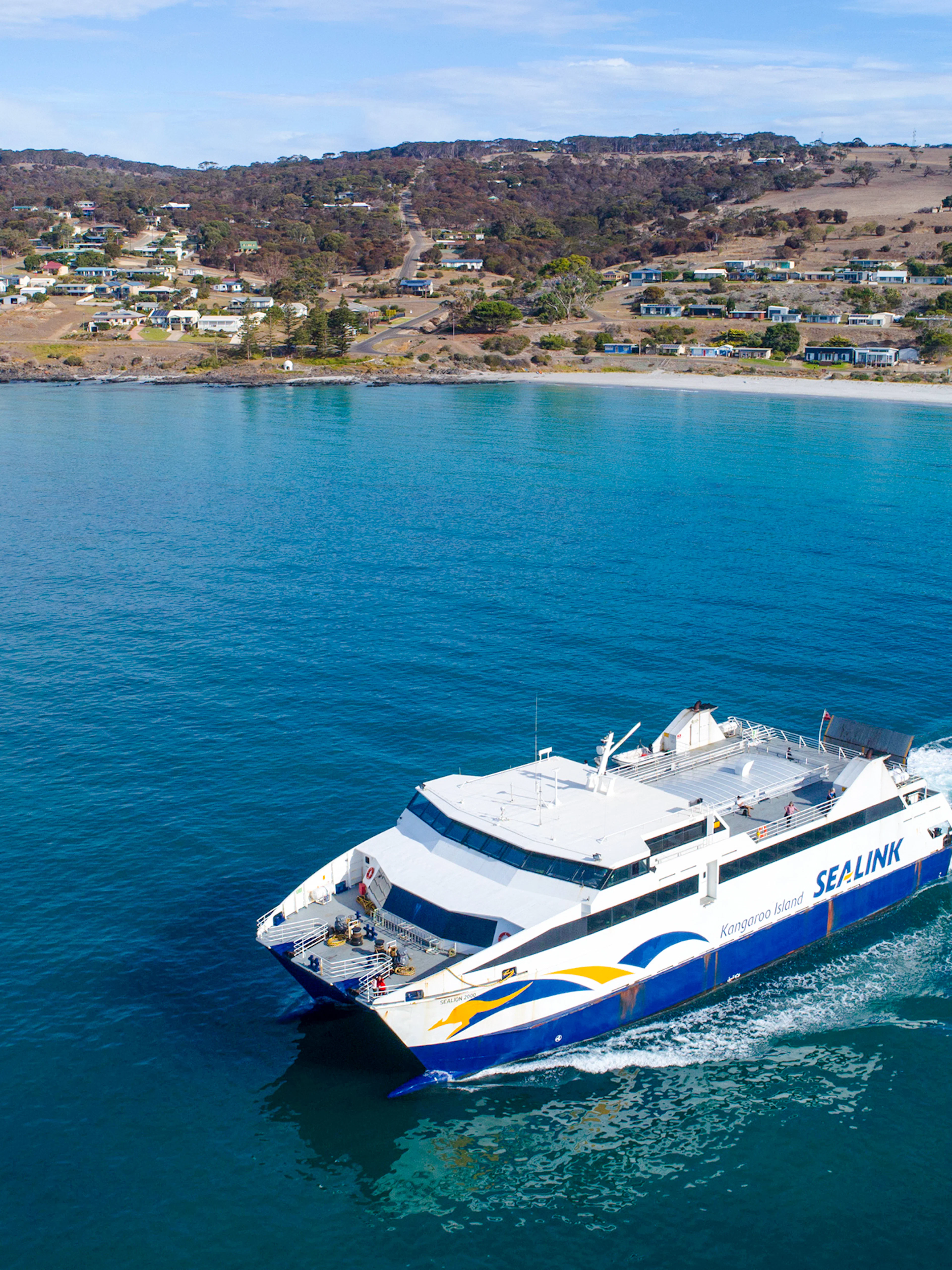 SeaLink ferry traveling from Kangaroo Island with coastal town in the background.
