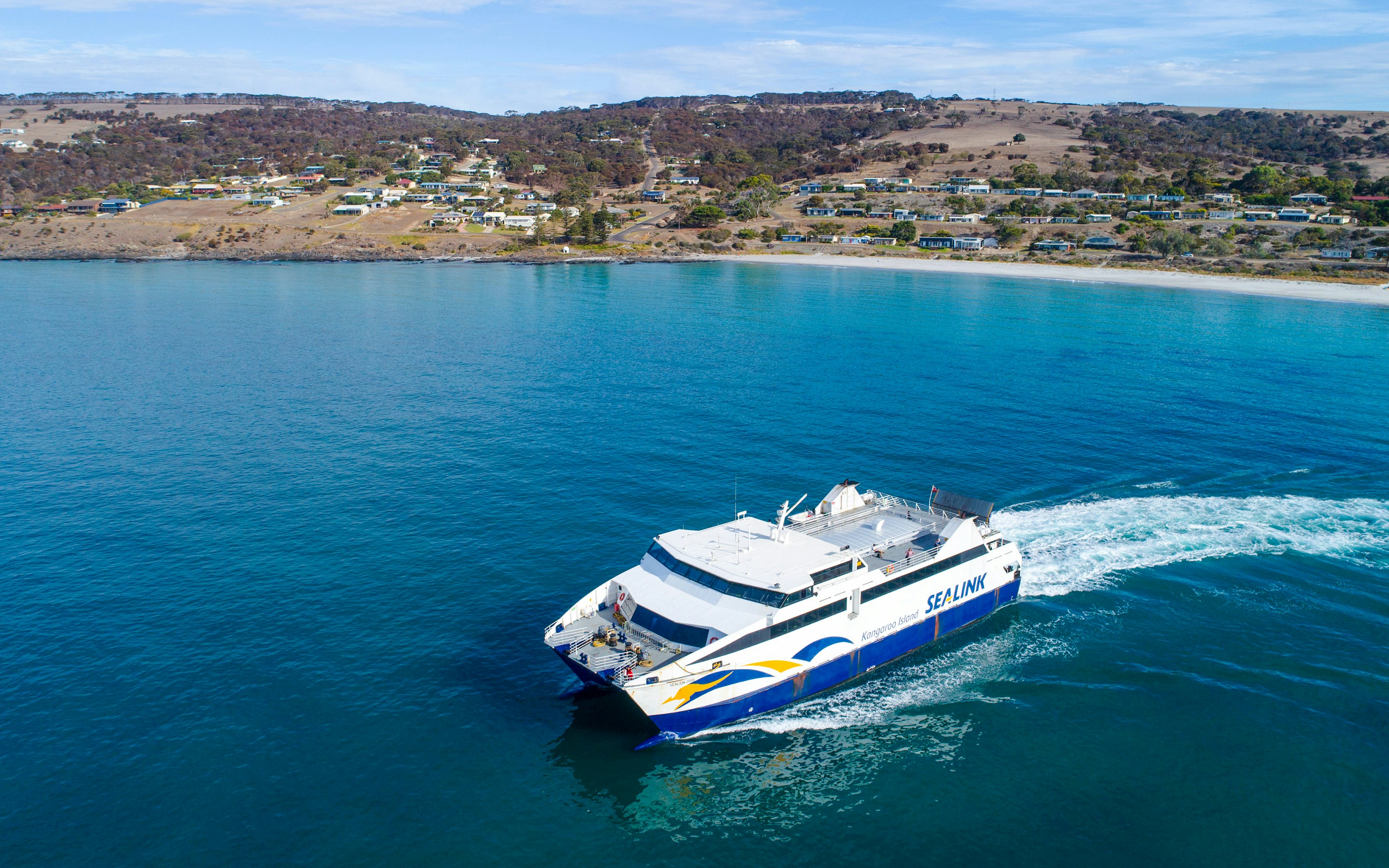 SeaLink ferry traveling from Kangaroo Island with coastal town in the background.
