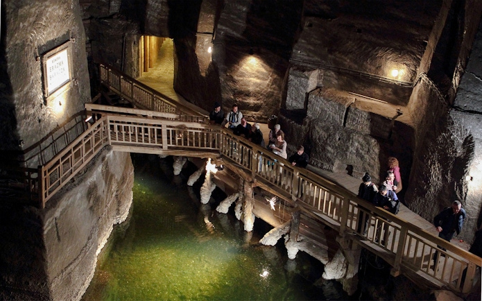 Visitors exploring the underground wooden walkway at Wieliczka Salt Mine.