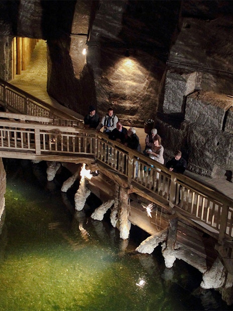 Visitors exploring the underground wooden walkway at Wieliczka Salt Mine.