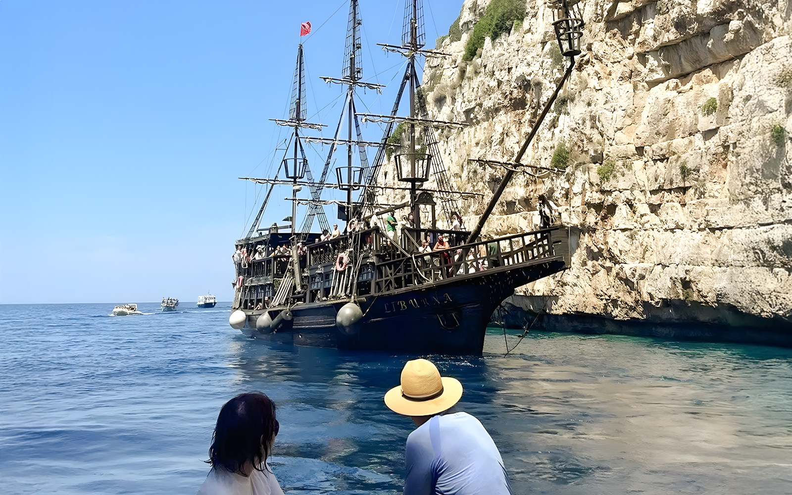 Pirate ship on Vlora's Ionian Odyssey tour, Albania, near rocky coastline.