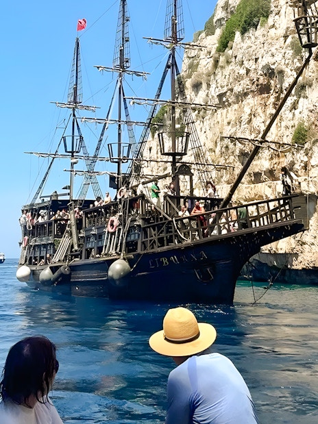 Pirate ship on Vlora's Ionian Odyssey tour, Albania, near rocky coastline.