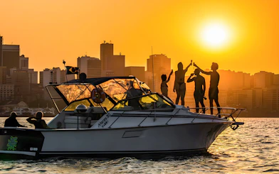 Tourists enjoying a sunset cruise in Rio de Janeiro with city skyline in the background.