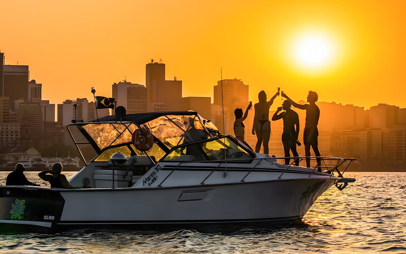 Tourists enjoying a sunset cruise in Rio de Janeiro with city skyline in the background.