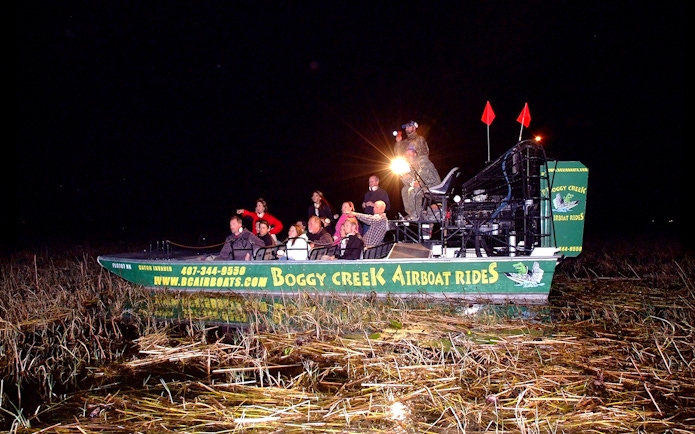 Guests on Boggy Creek night airboat tour in marshland.