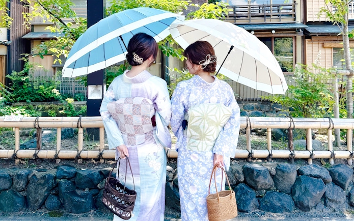 Individuals in kimonos with umbrellas in historic Kyoto district, Japan.