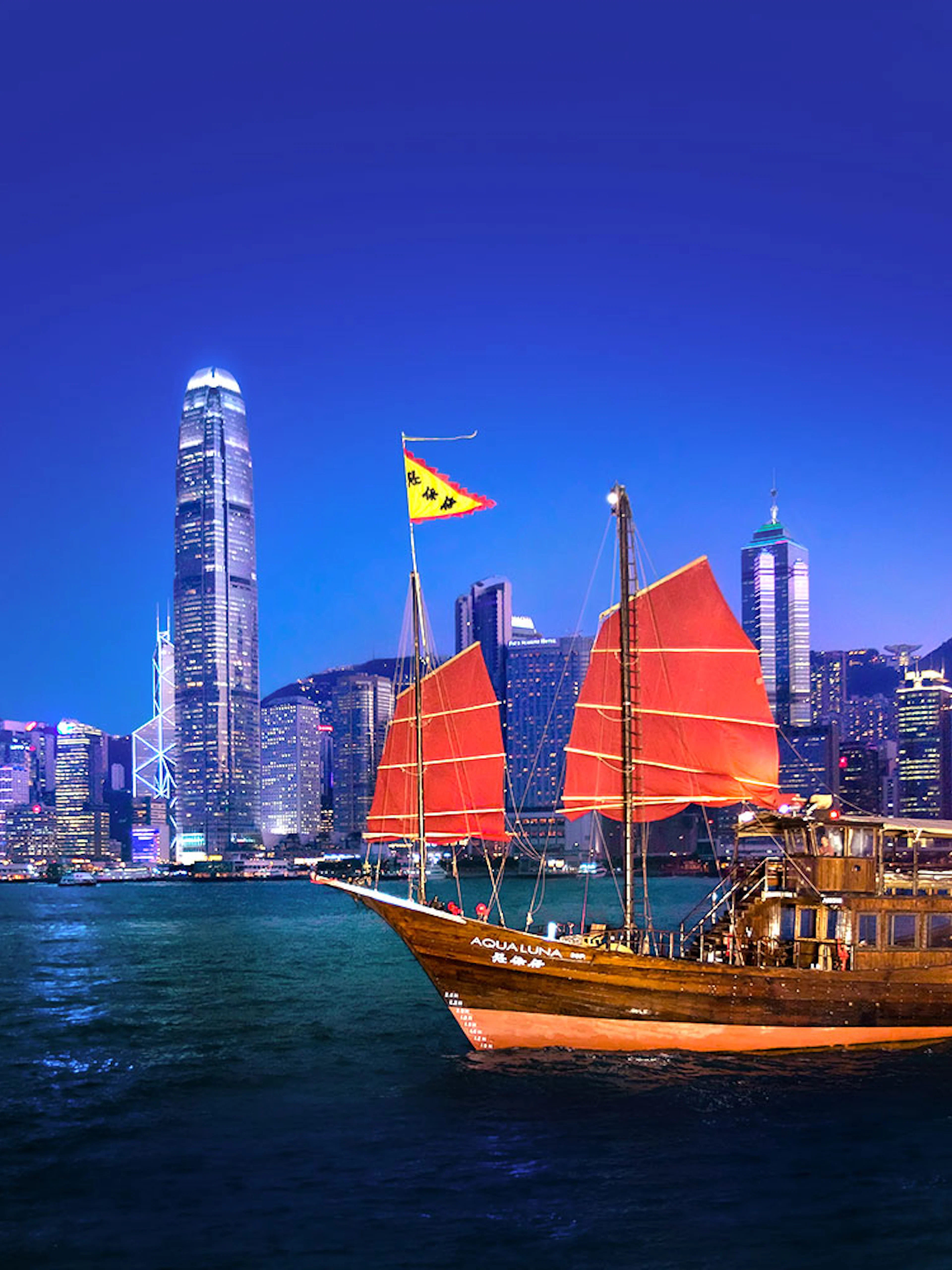 Traditional junk boat with red sails in Hong Kong harbor during AquaLuna day tour.