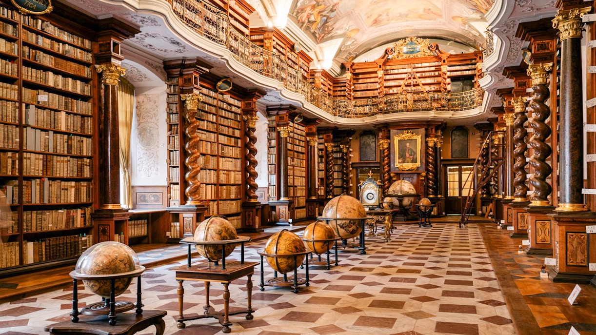 Prague Klementinum Library interior with ornate bookshelves and globes.