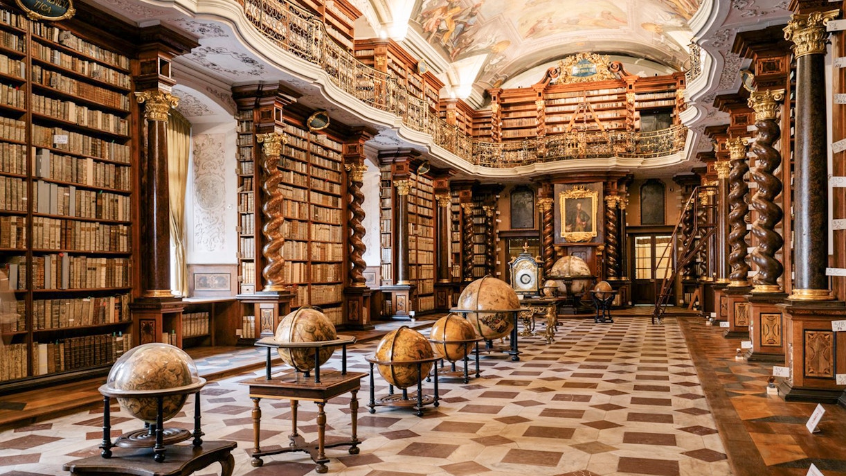 Prague Klementinum Library interior with ornate bookshelves and globes.