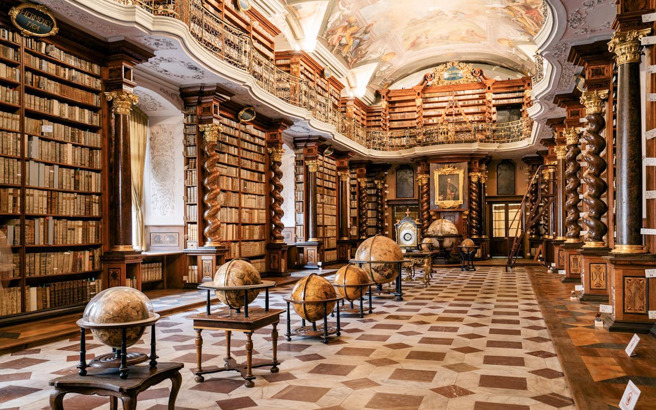 Prague Klementinum Library interior with ornate bookshelves and globes.