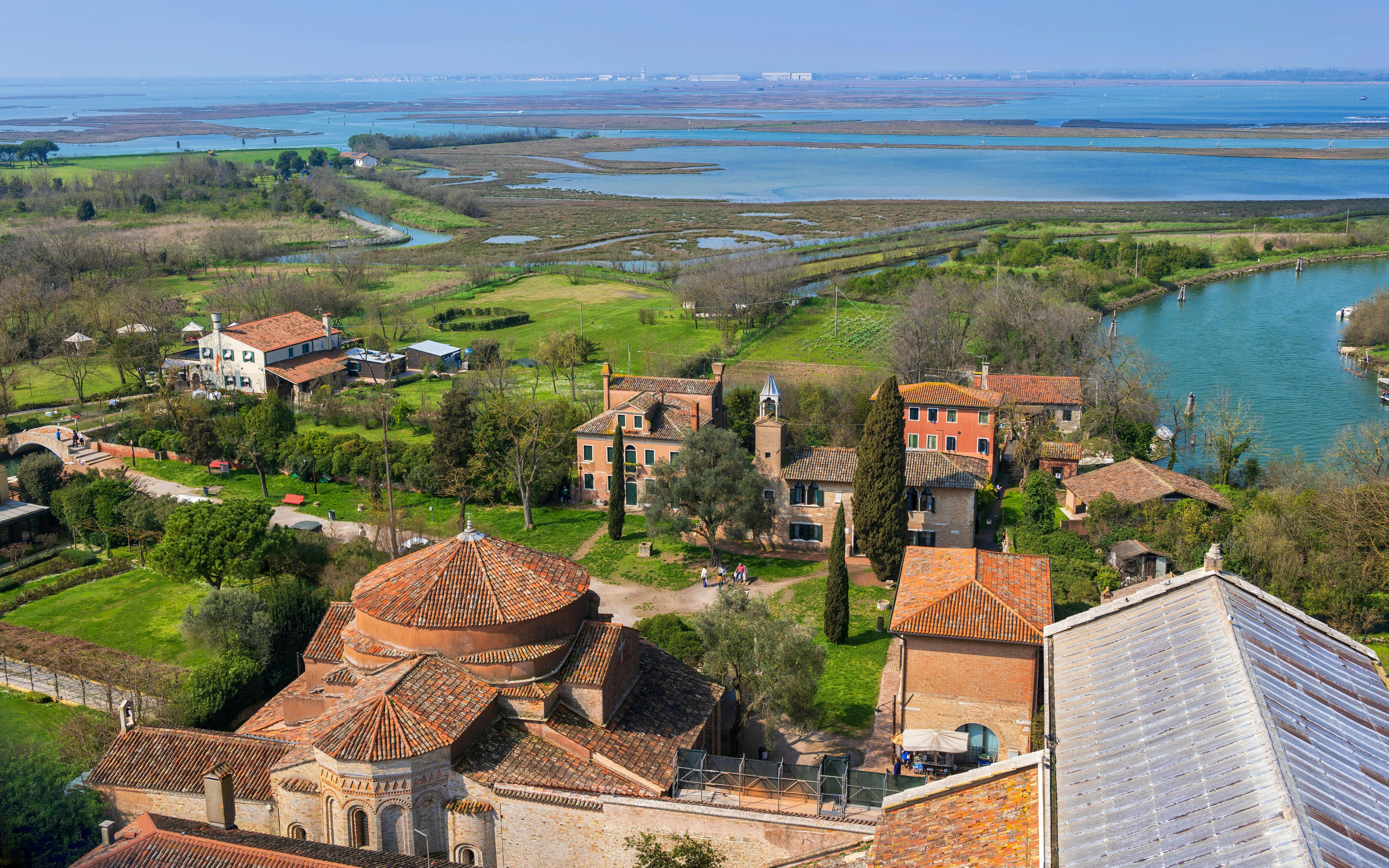 Aerial view of Torcello with historic buildings, lush greenery, and surrounding waterways.