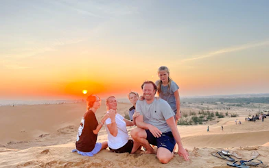 Family enjoying sunset on sand dunes during Mui Ne Jeep Tour with ATV Ride, Ho Chi Minh City.