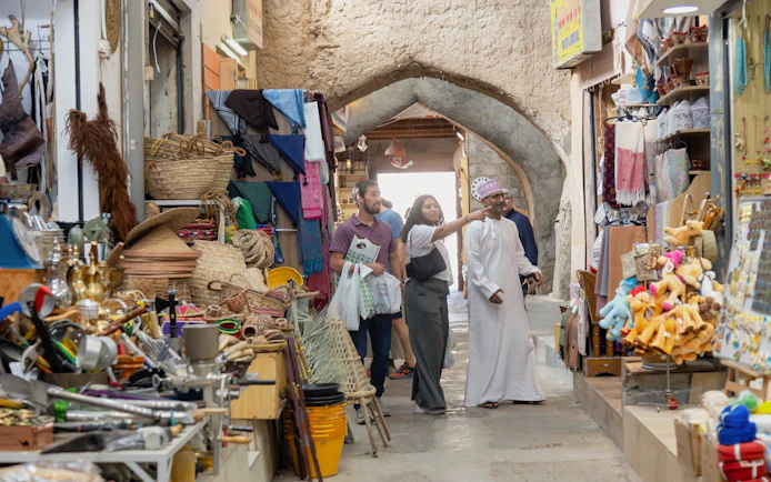 Tourist with guide exploring shops in Nizwa souk, Oman.